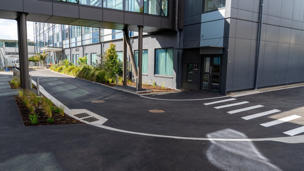 Hotmix access road with kerbs, planting and a pedestrian crossing on a hospital campus