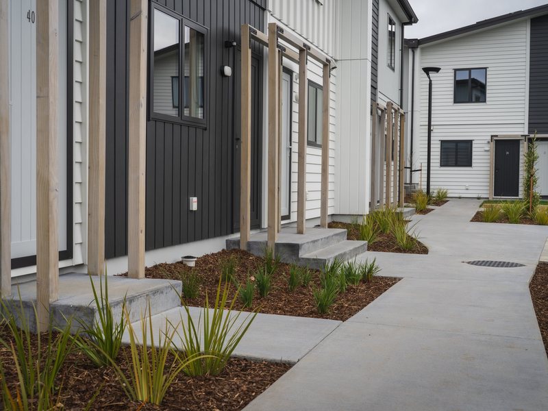 Concrete paths, planting and timber entry frames at a housing development, Horahora