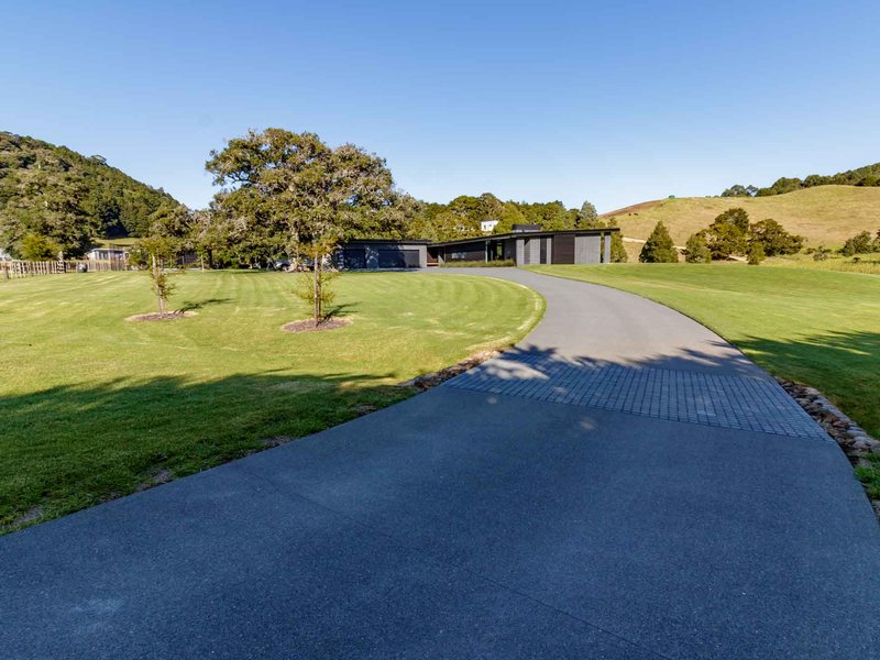 Exposed aggregate concrete driveway with a paver band leading to a modern home