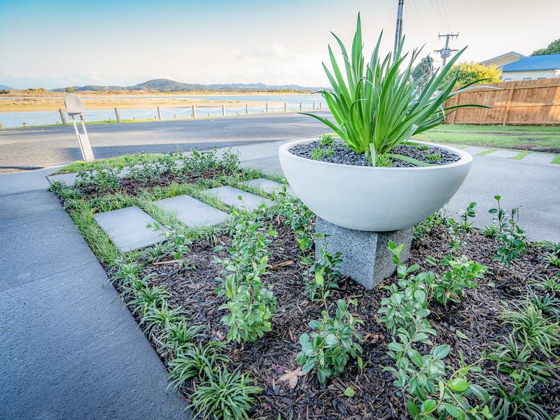 Concrete driveway beside new landscaping with a feature planter