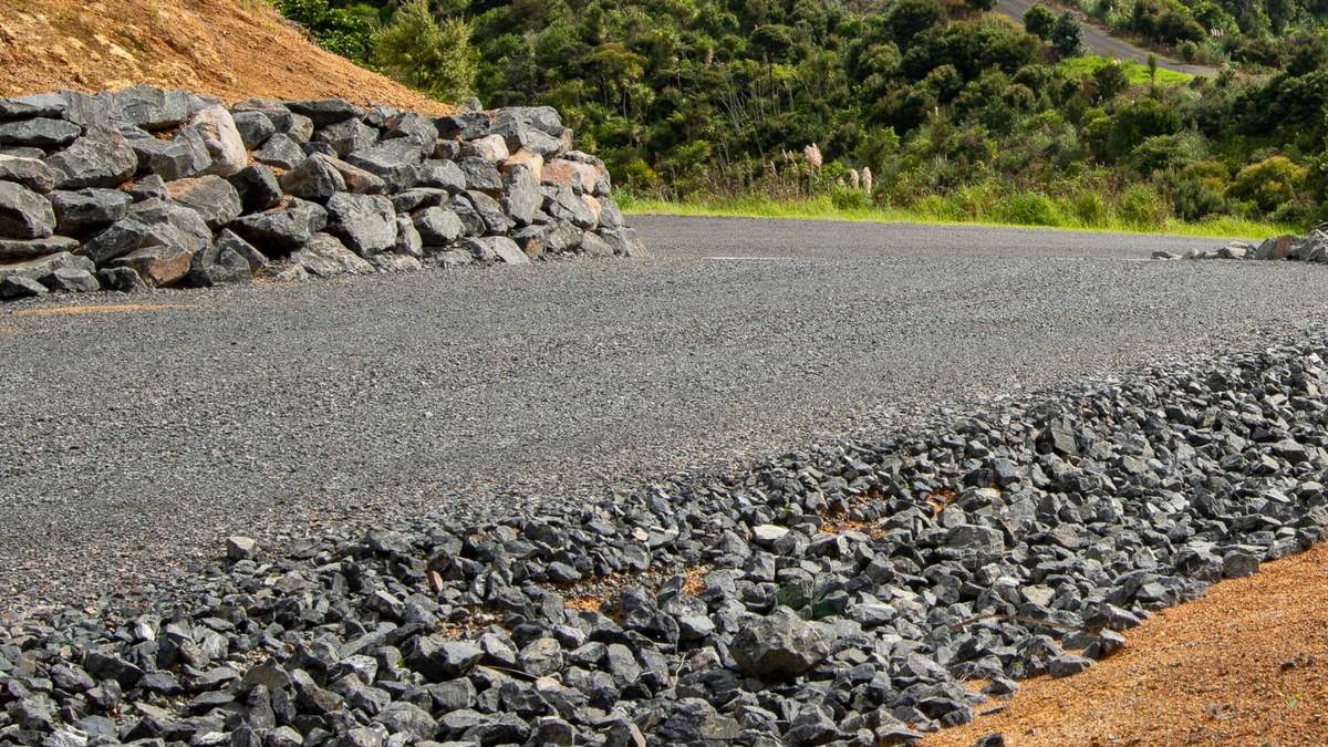 Rural metal driveway with a rock wall and rock-lined drain