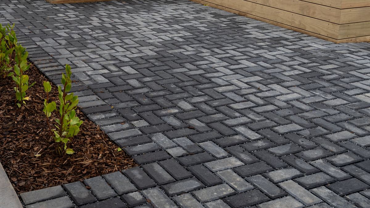 Herringbone permeable pavers beside a planted garden