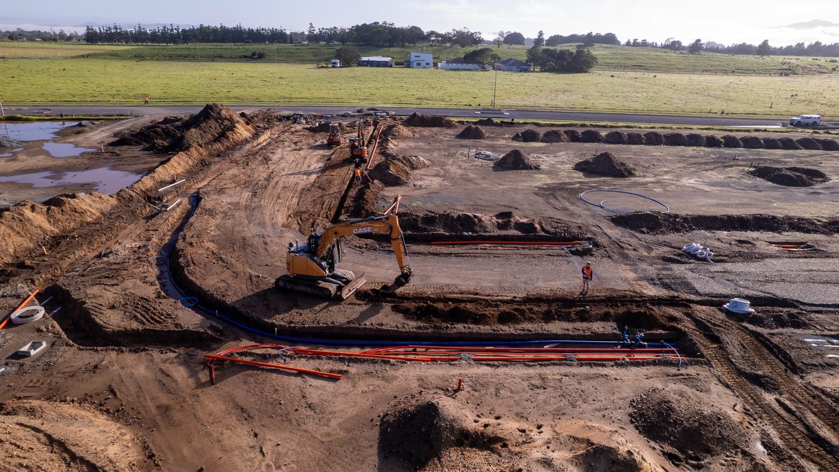 Excavator laying a water main and ducts in a new subdivision at Marsden City