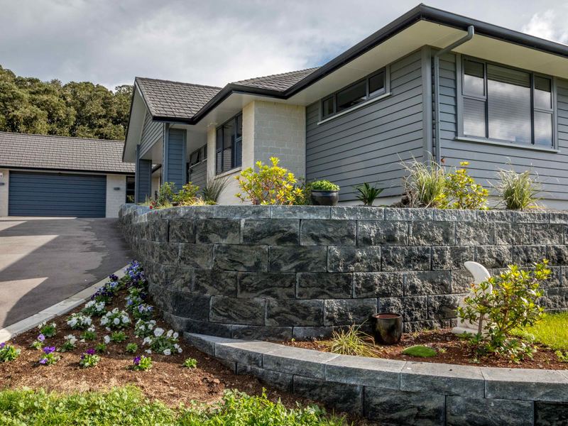 Curved block retaining wall with new garden planting in front of a home