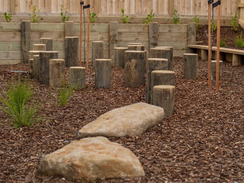 Nature play space with timber posts, stepping stones and planting