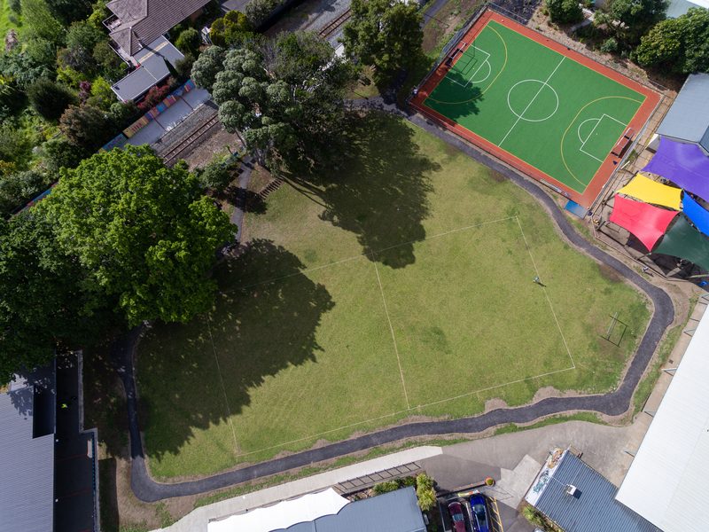 Aerial view of a school turf court and asphalt path around the field