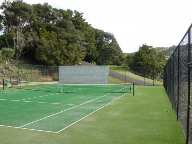 Home tennis court with a practice wall and perimeter fencing