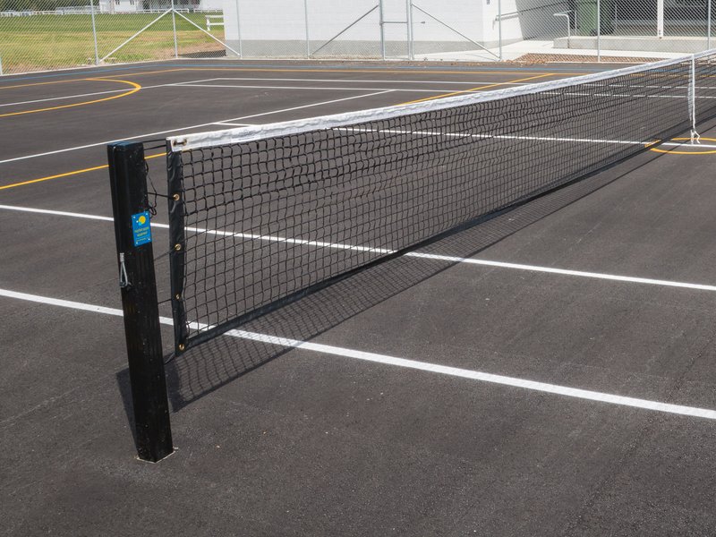 Tennis net on a multi-sport asphalt court beside new clubrooms