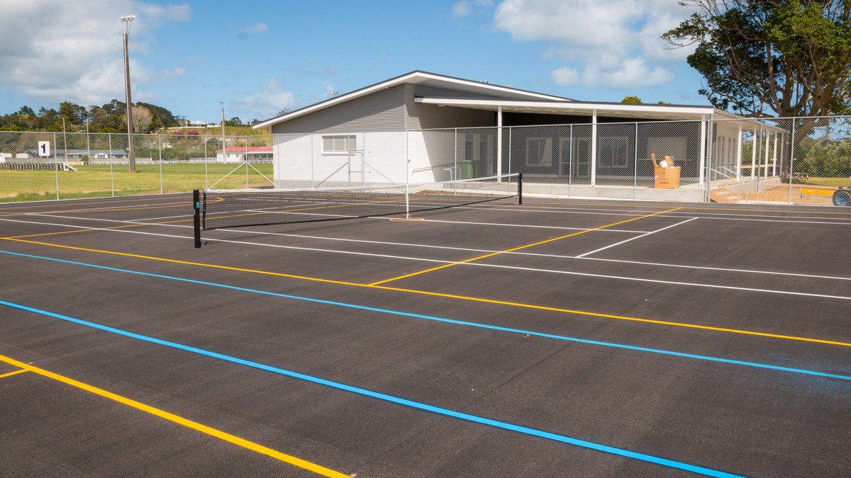 Multi-sport court with fencing, lighting and nets beside clubrooms