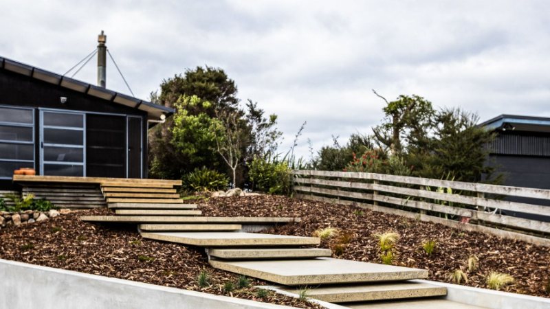 Wide timber steps through new garden beds beside a modern home